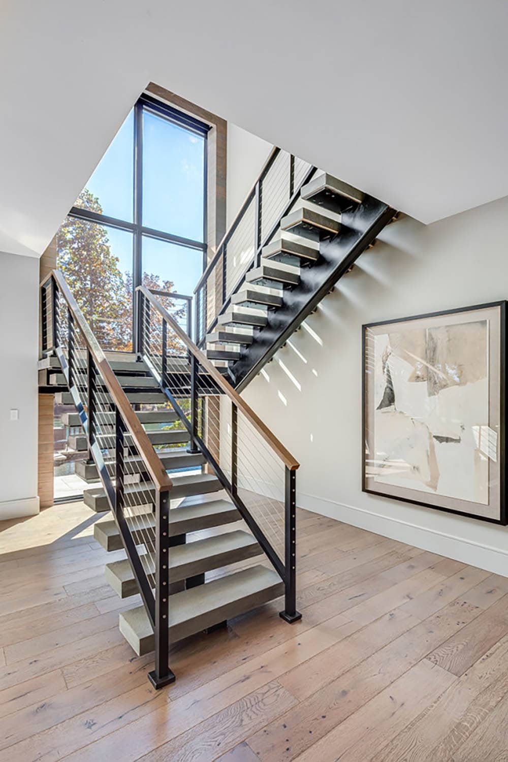 Modern floating staircase with cable railings and floor-to-ceiling window