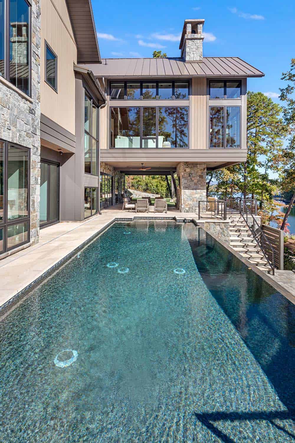 Rear exterior view of the lake house with infinity-edge pool and covered patio