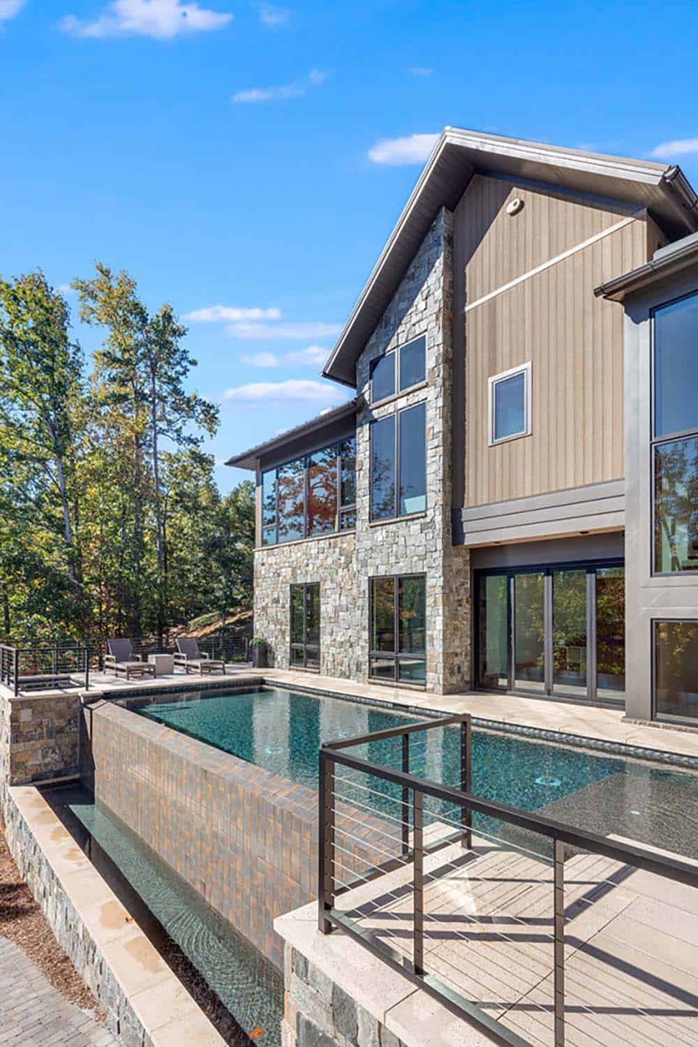Side exterior view showing stone and wood siding with pool and lake in background