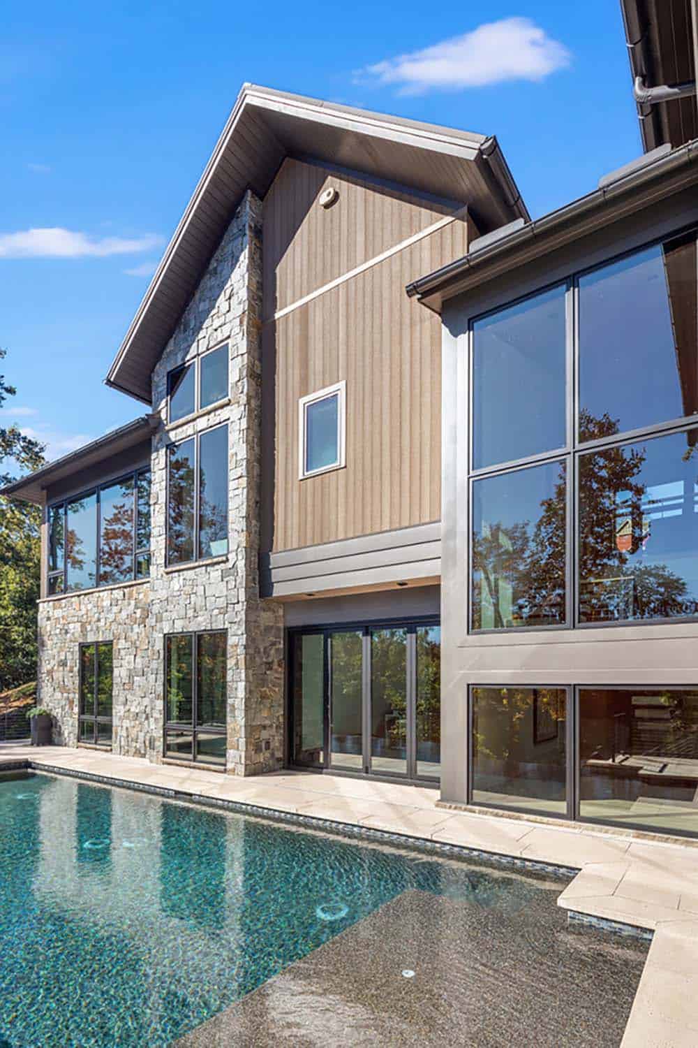 Close-up exterior view of stone and vertical wood siding with large windows