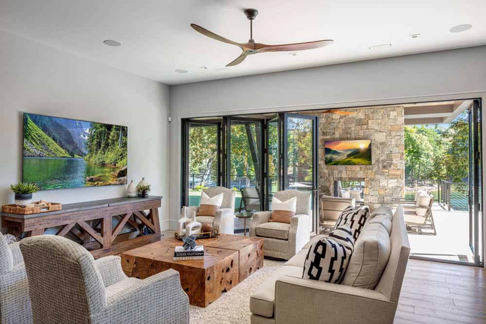 Living room open to covered patio with stone fireplace visible through folding doors