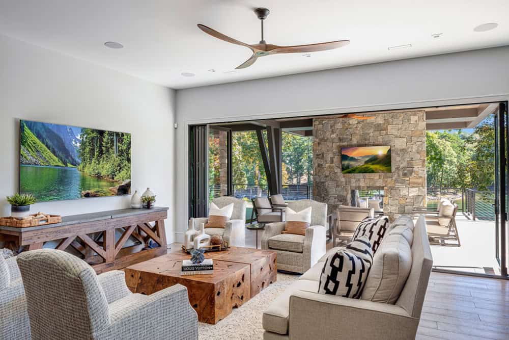Wide view of living room with TV, sofas, and open folding doors to outdoor lounge