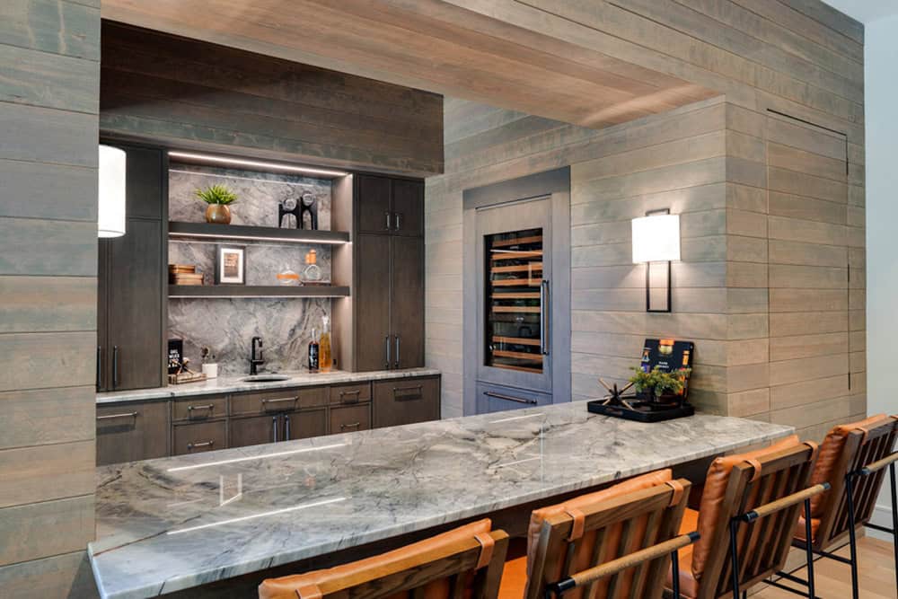 Wet bar with marble countertop, wine fridge, and leather bar stools