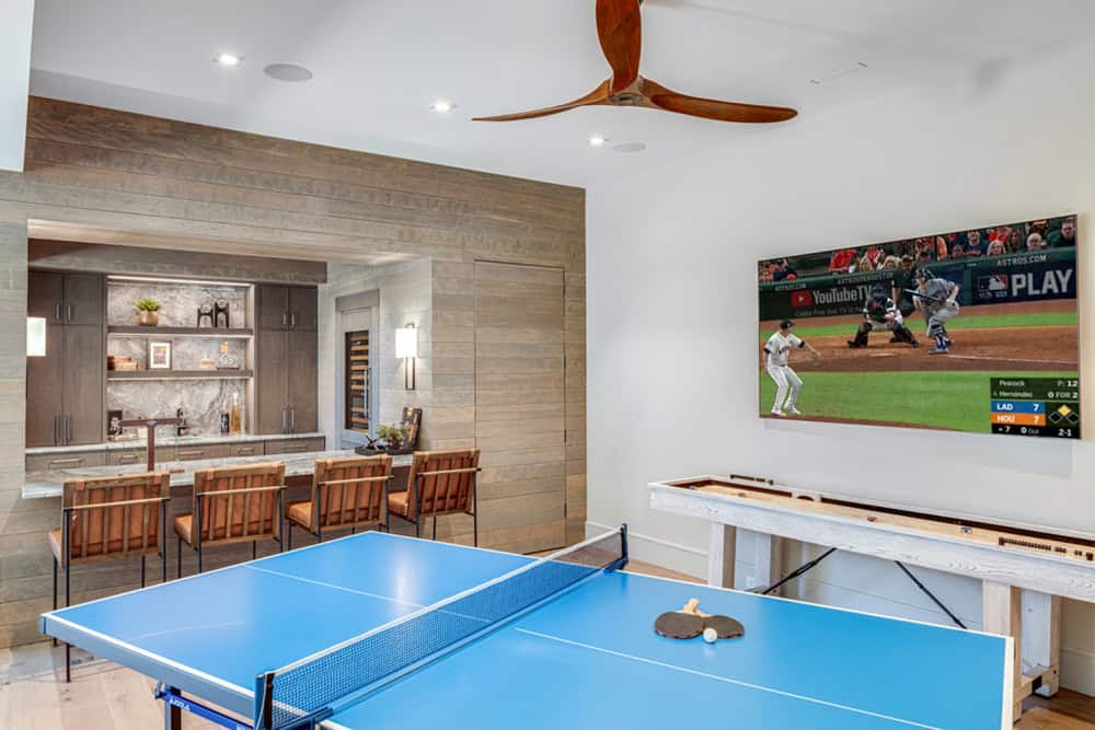 Game room with ping pong table, shuffleboard, TV, and wet bar