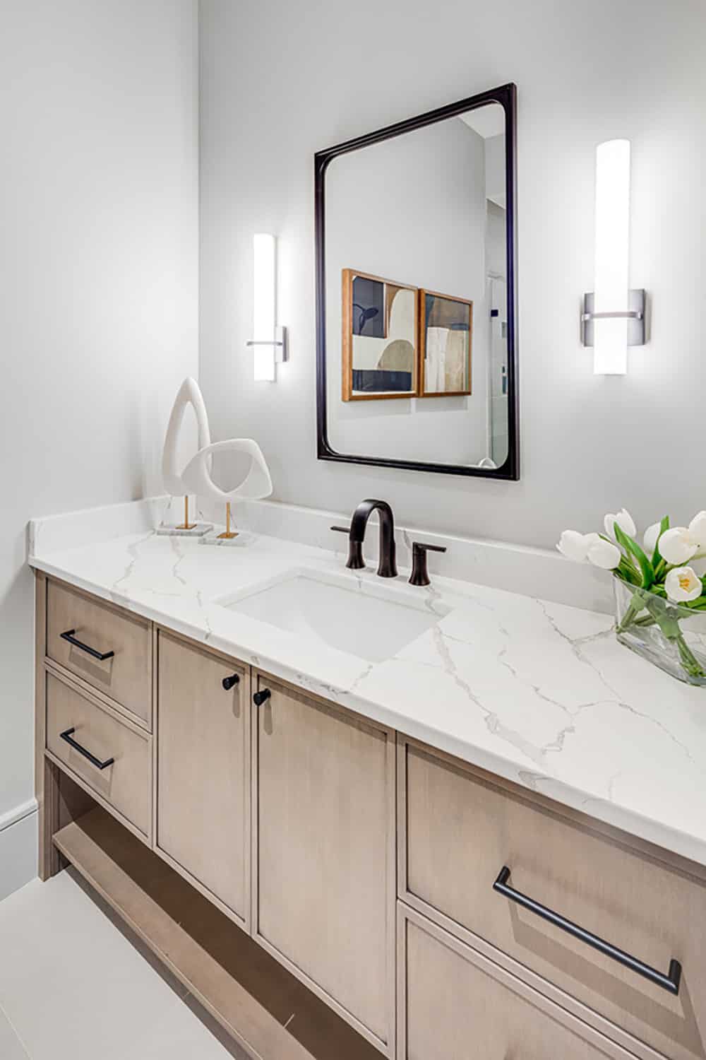 Bathroom vanity with marble countertop, black fixtures, and framed mirror
