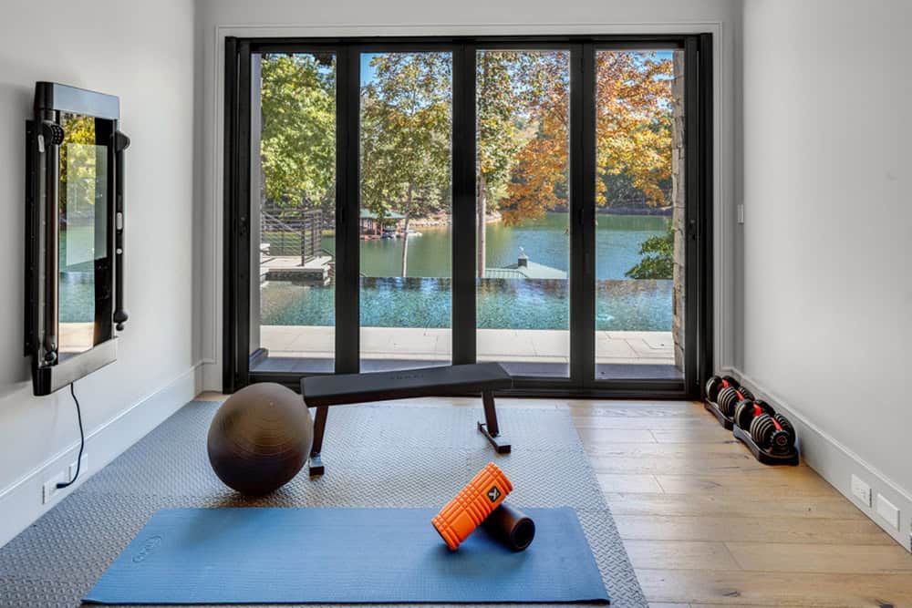 Home gym with exercise equipment and folding glass doors overlooking the lake and pool