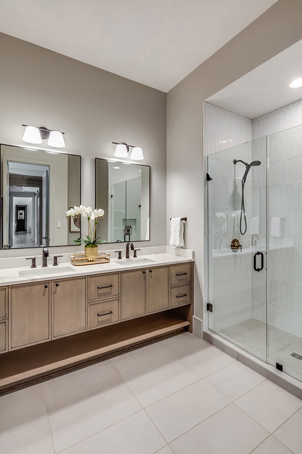 Primary bathroom with double vanity and glass-enclosed tiled shower