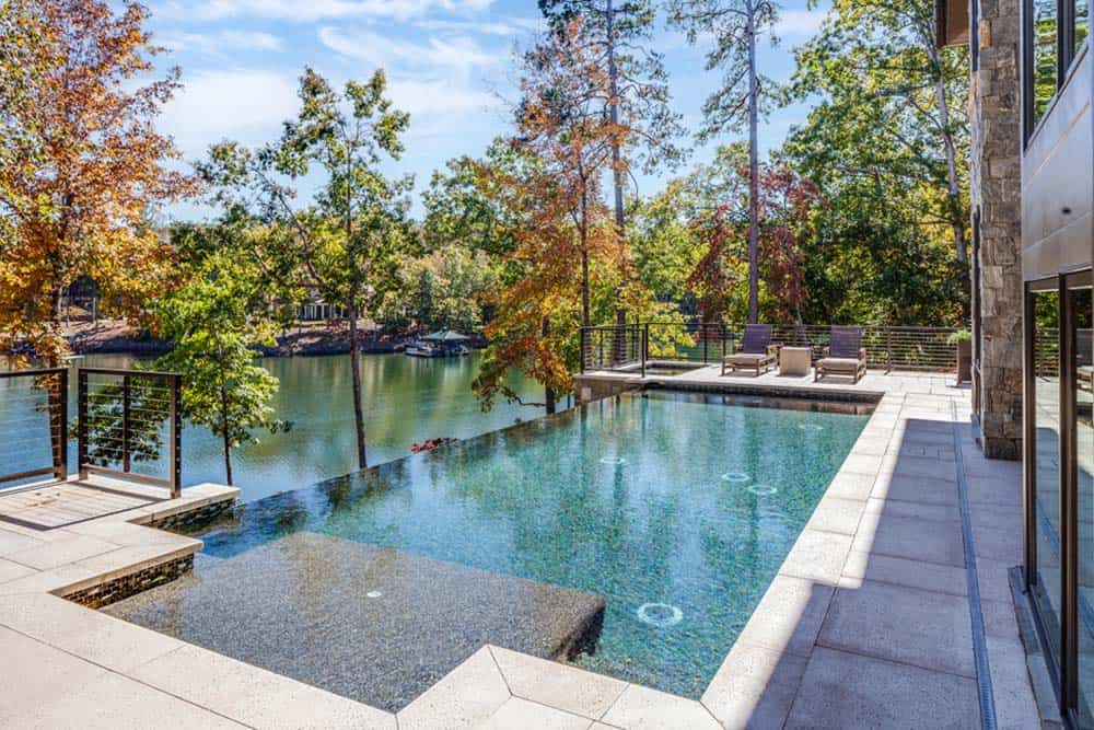 Infinity-edge pool overlooking a tree-lined lake in fall foliage