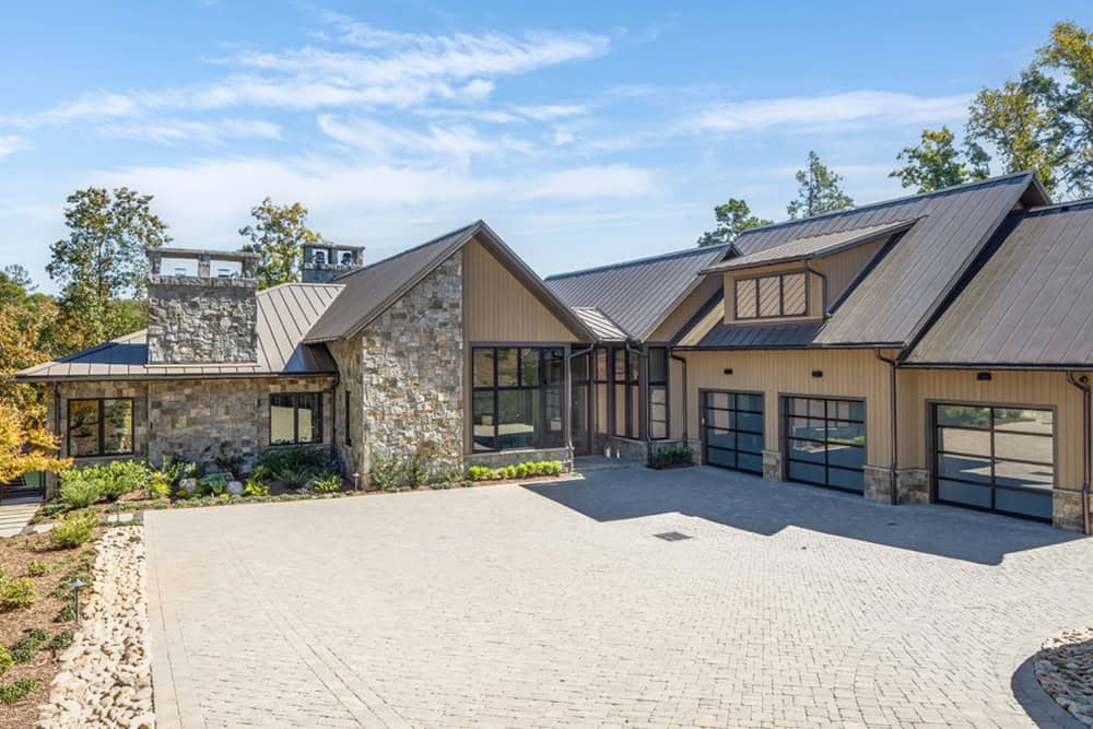 Front exterior of the lake house showing stone accents, metal roof, and motor court