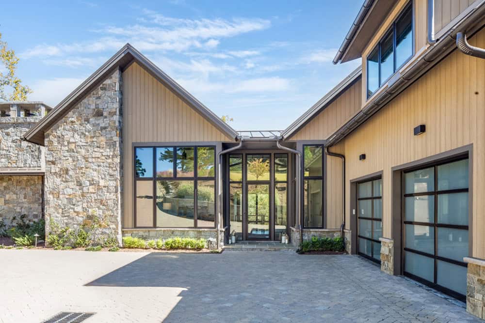 Front entrance with glass door flanked by tall windows and a two-car garage