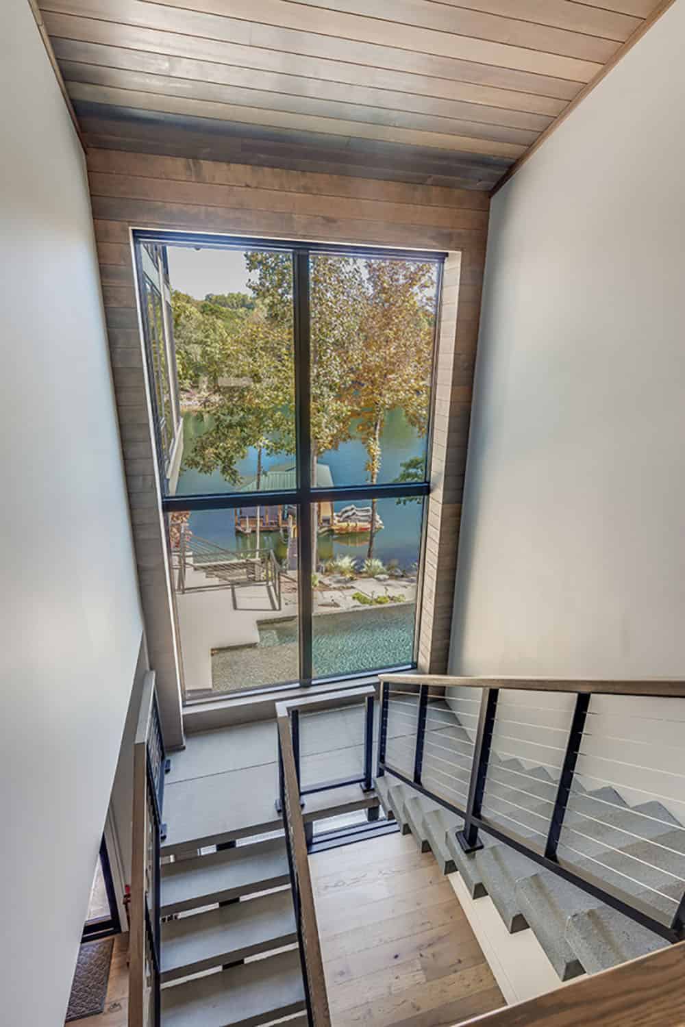 Stairwell landing with floor-to-ceiling window overlooking the lake and dock