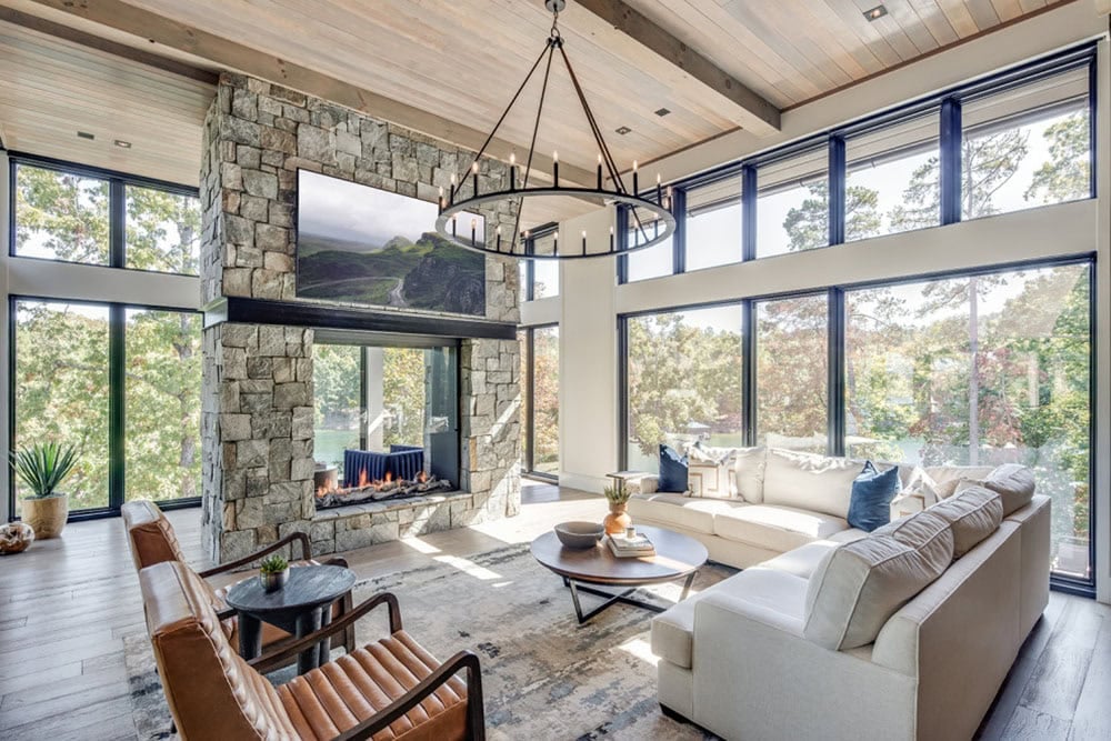 Living room with leather chairs, sectional sofa, and floor-to-ceiling lake-view windows