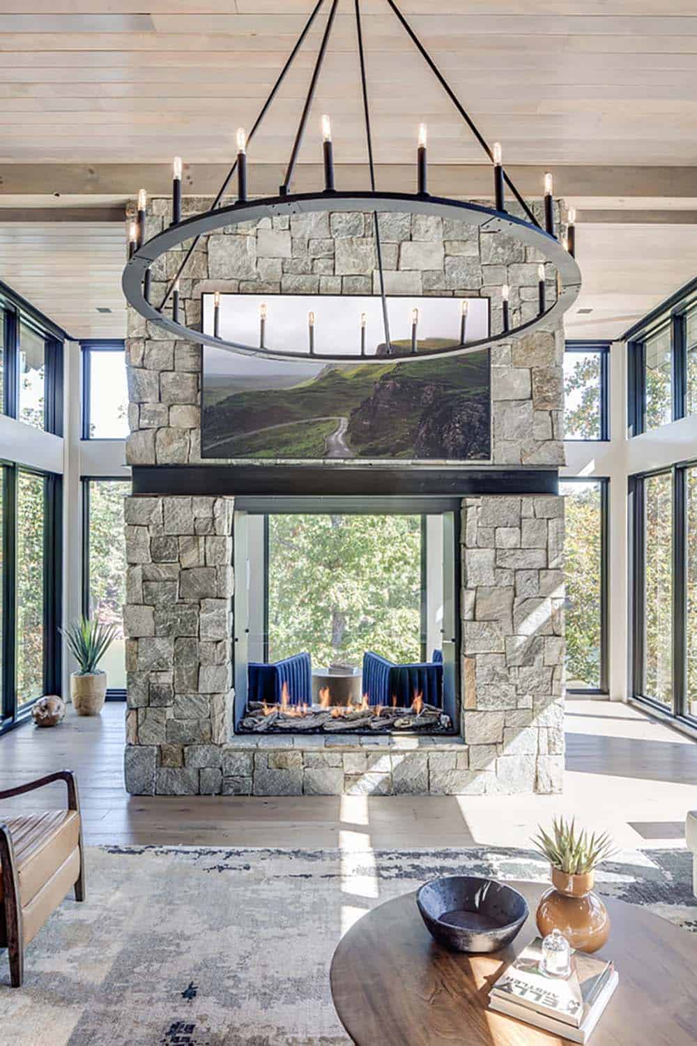 Close-up of the two-sided stone fireplace with candle-ring chandelier and mounted TV
