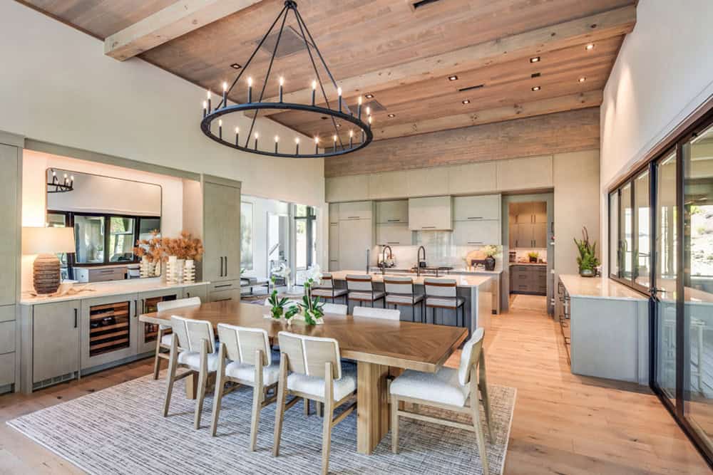 Open kitchen and dining area with wagon-wheel chandelier and wood plank ceiling