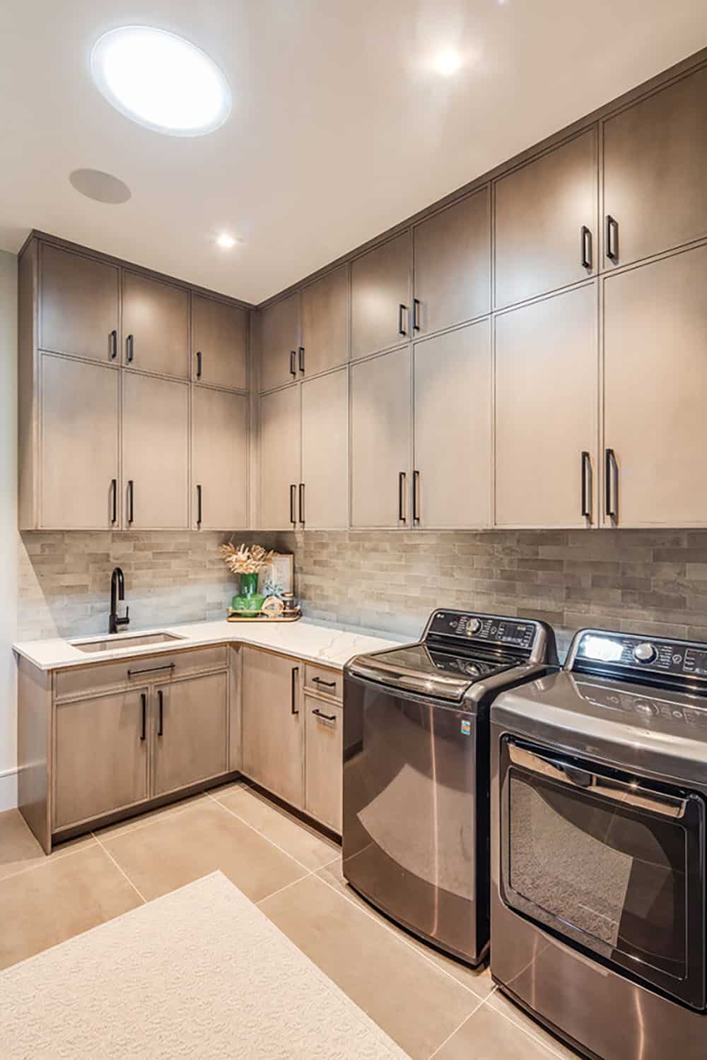 Laundry room with floor-to-ceiling cabinets, sink, and stacked appliances