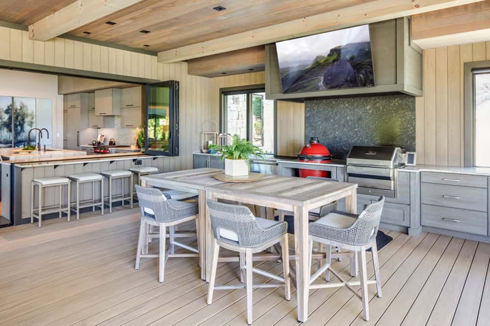 Outdoor kitchen and dining space opening to the indoor kitchen through a pass-through window
