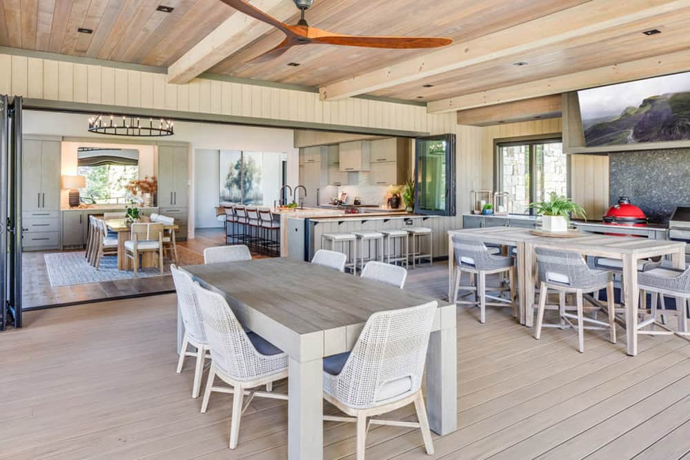 Wide view of the covered outdoor living, dining, and kitchen area under a wood ceiling