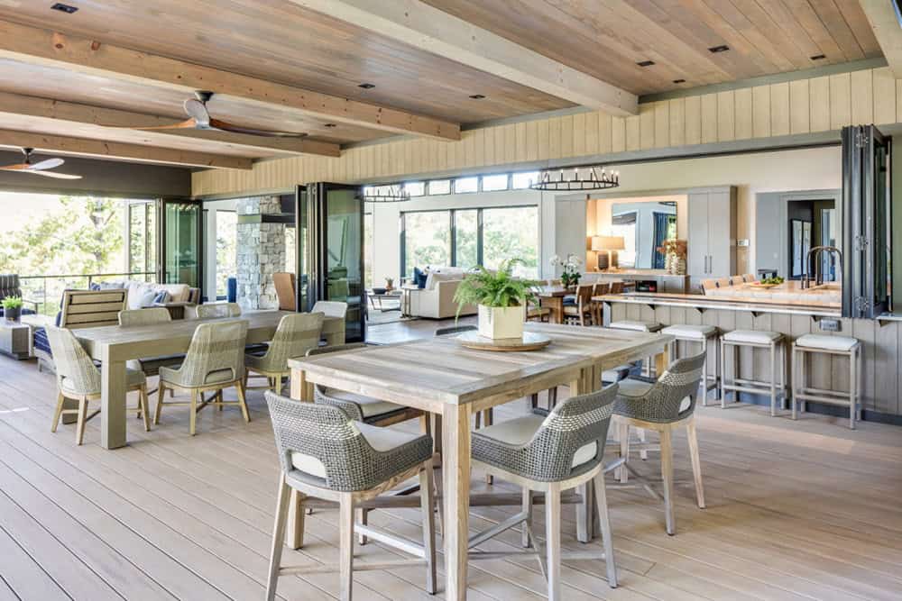 Expansive covered deck with multiple dining and lounge areas overlooking the lake