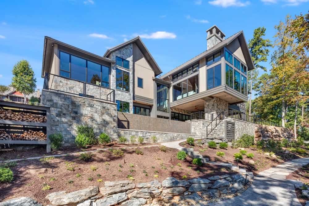 Rear exterior of the lake house showing tiered stone retaining walls and landscaping