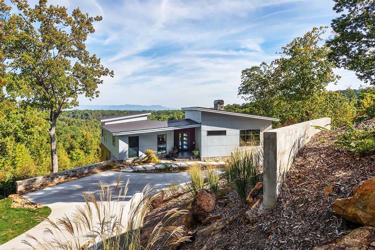 Modern hillside home exterior with stacked stone retaining wall and driveway
