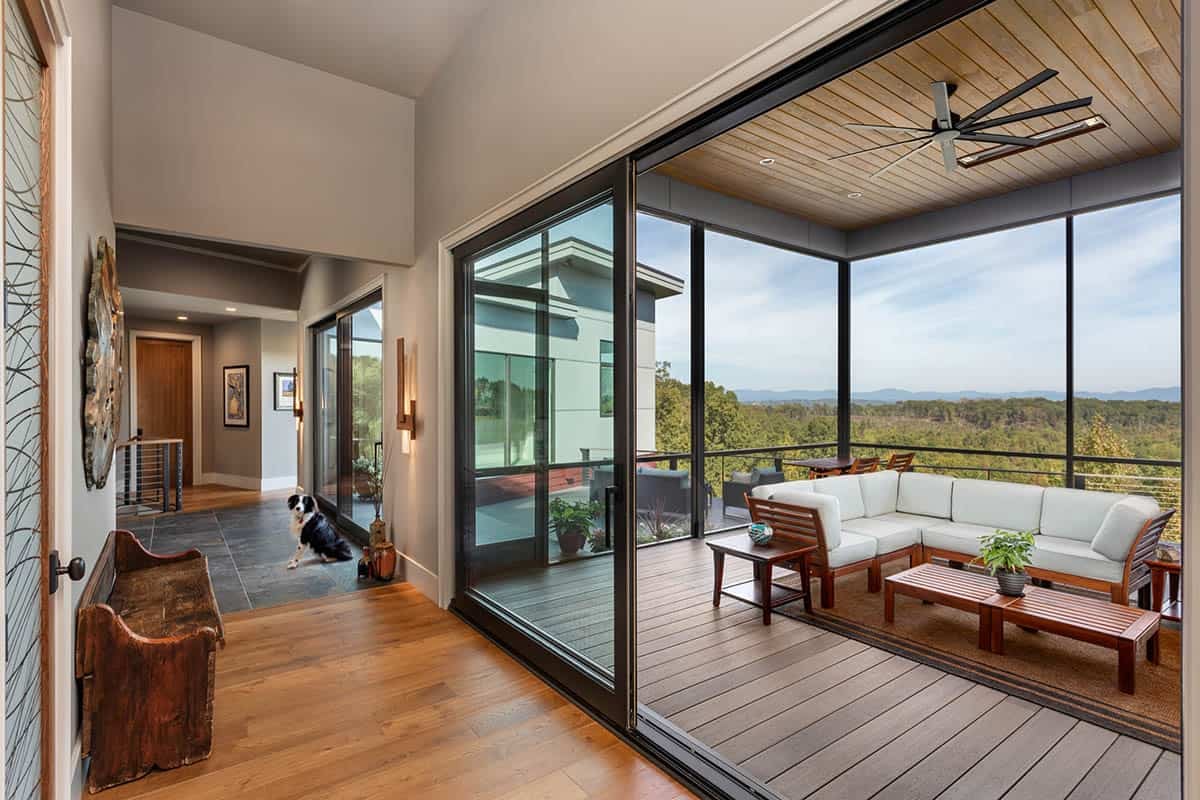 Hallway leading to screened porch with sectional sofa and dog on tile floor