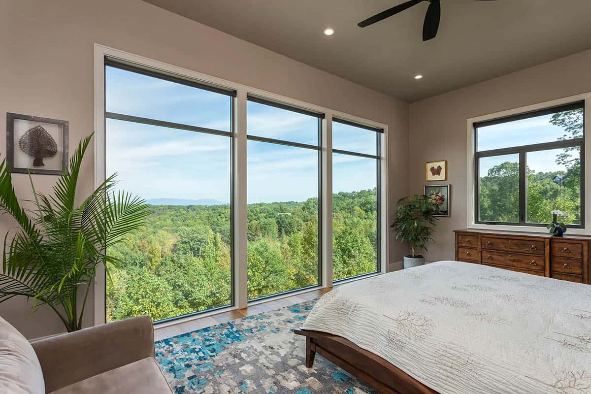 Bedroom with floor-to-ceiling windows overlooking forested mountains