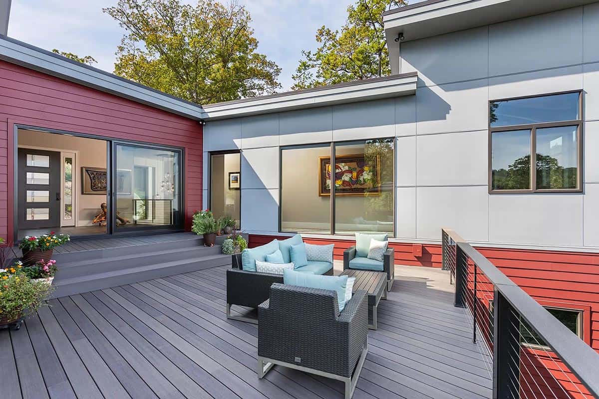 Outdoor deck with wicker furniture between red and white siding walls