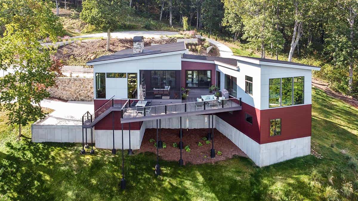 Aerial view of home's rear deck on stilts above sloped wooded yard