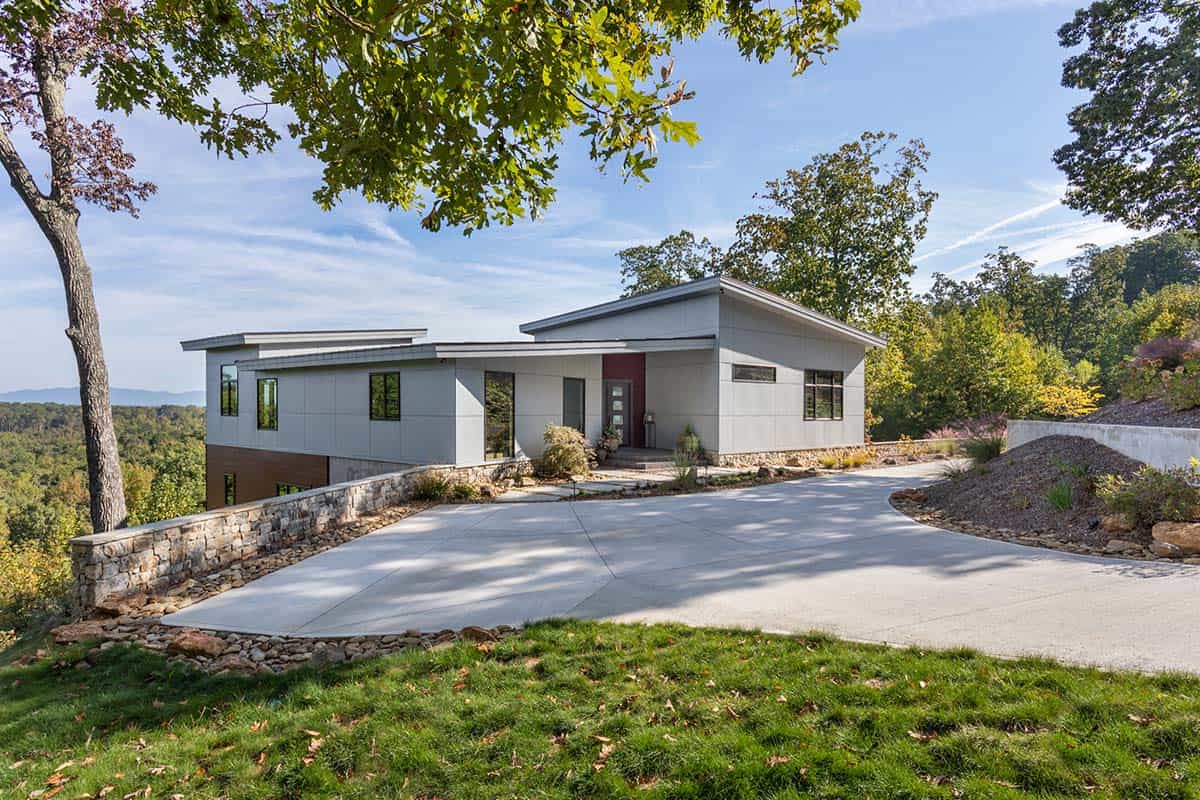 Front exterior of modern home with red door and curved driveway