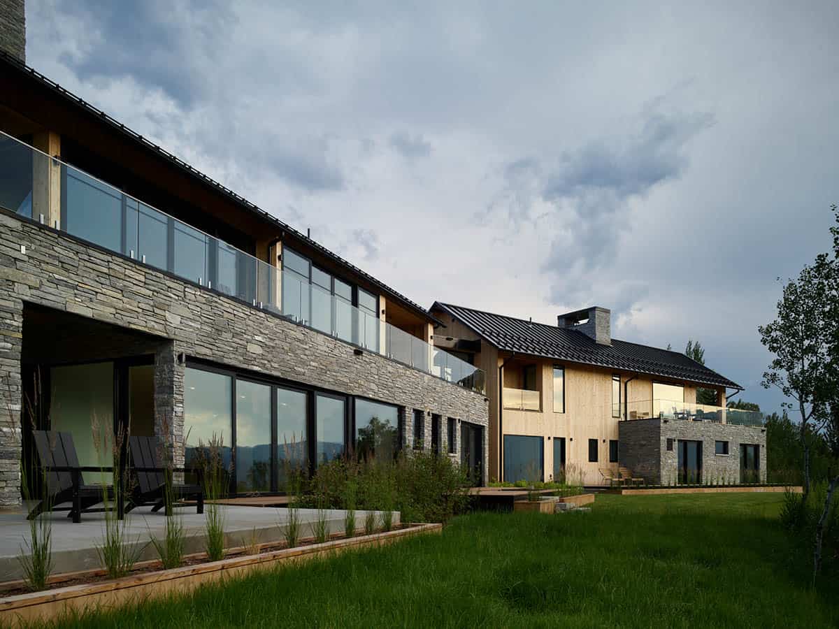 Contemporary stone and wood home exterior under a cloudy evening sky
