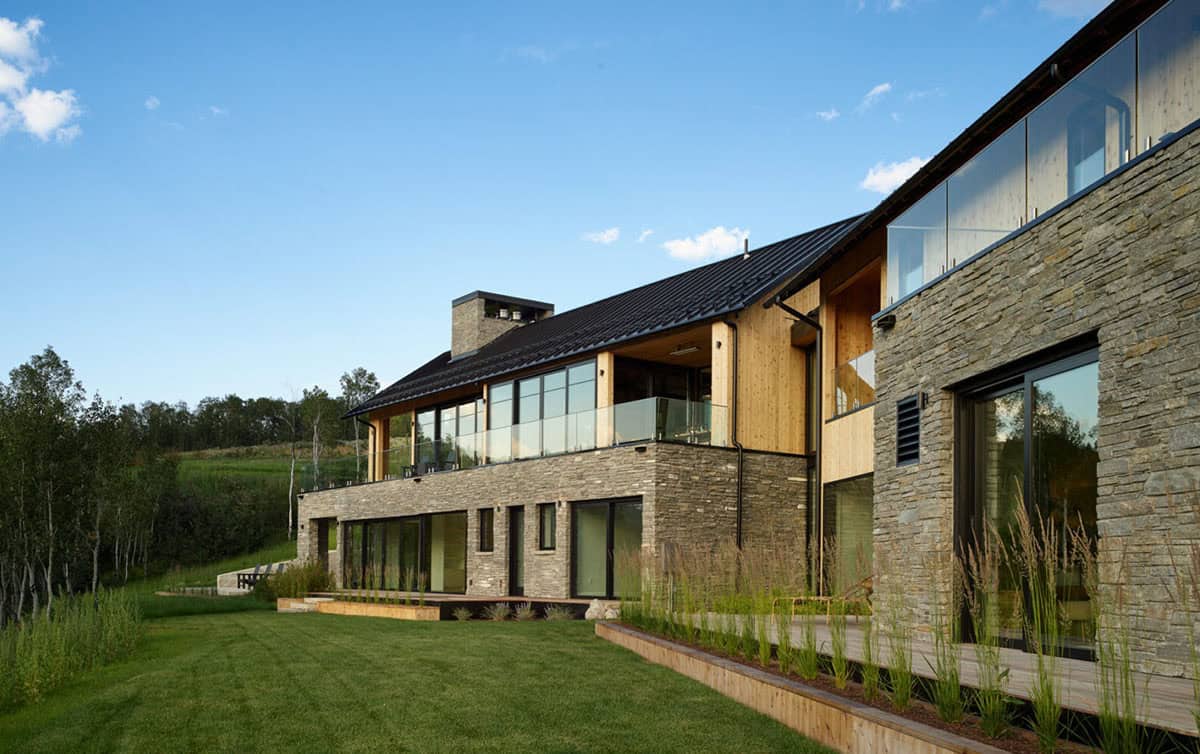 Stone and wood facade with black metal roof overlooking green landscape