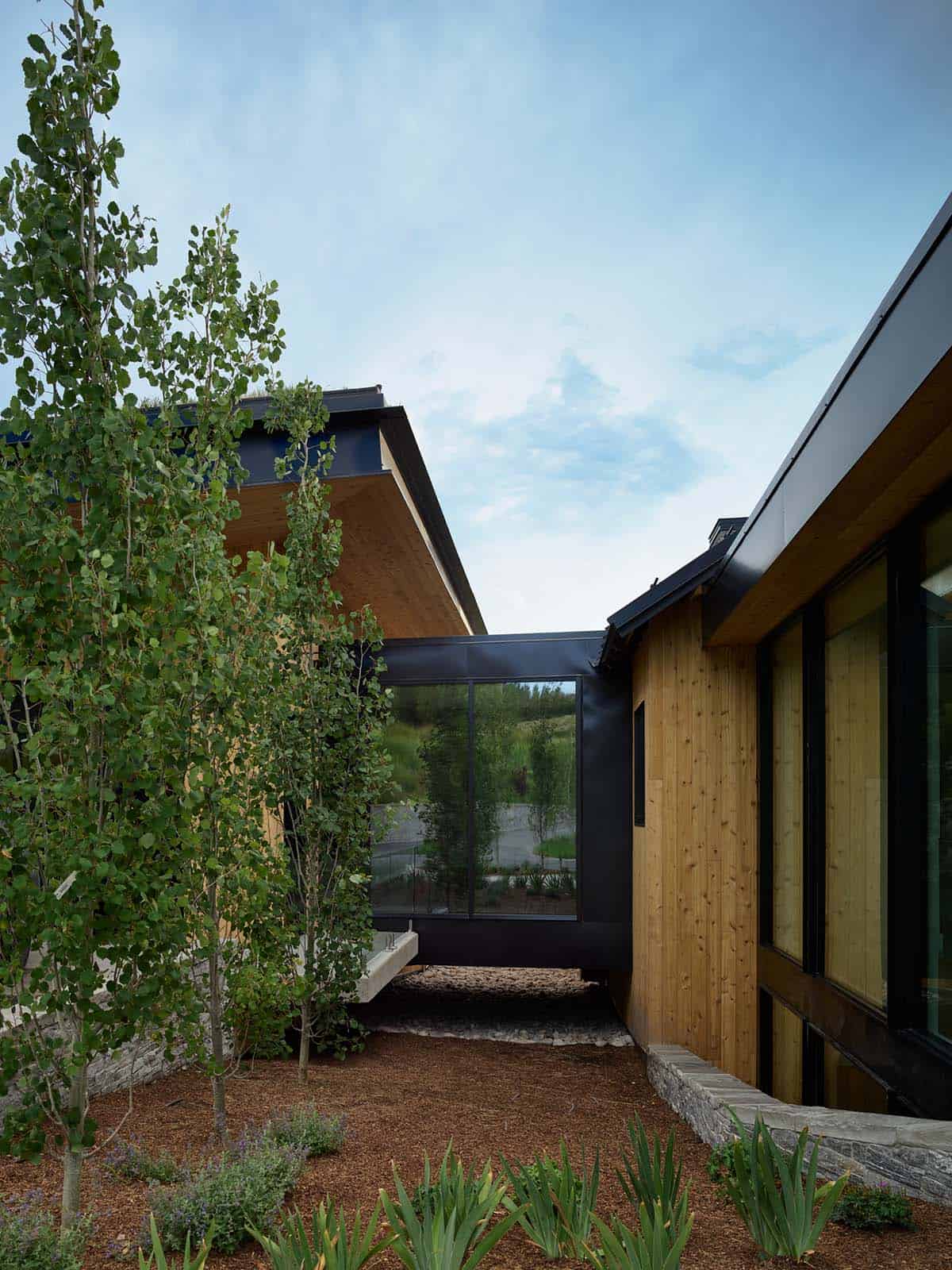 Exterior corridor connecting wood-clad home sections with black metal roof