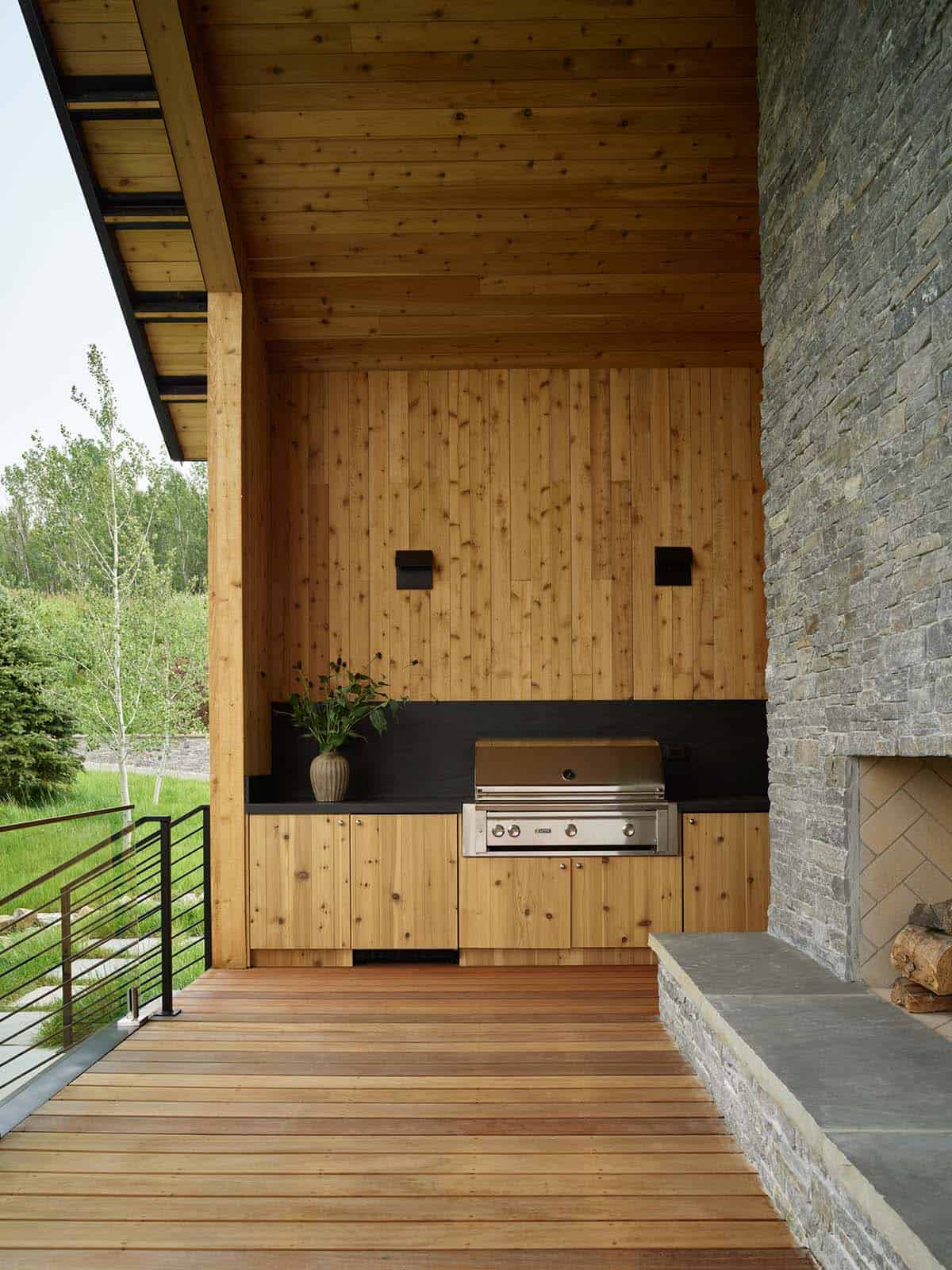 Outdoor kitchen with grill, wood cabinetry, and stone fireplace