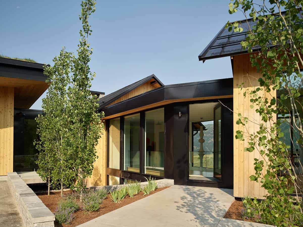 Wood-clad entryway with black steel door frame and mountain reflection