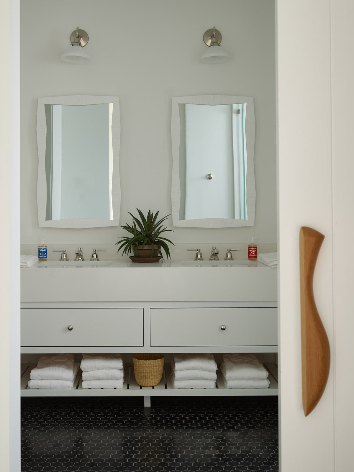 Double vanity bathroom with wave-edged mirrors and black hexagon tile floor