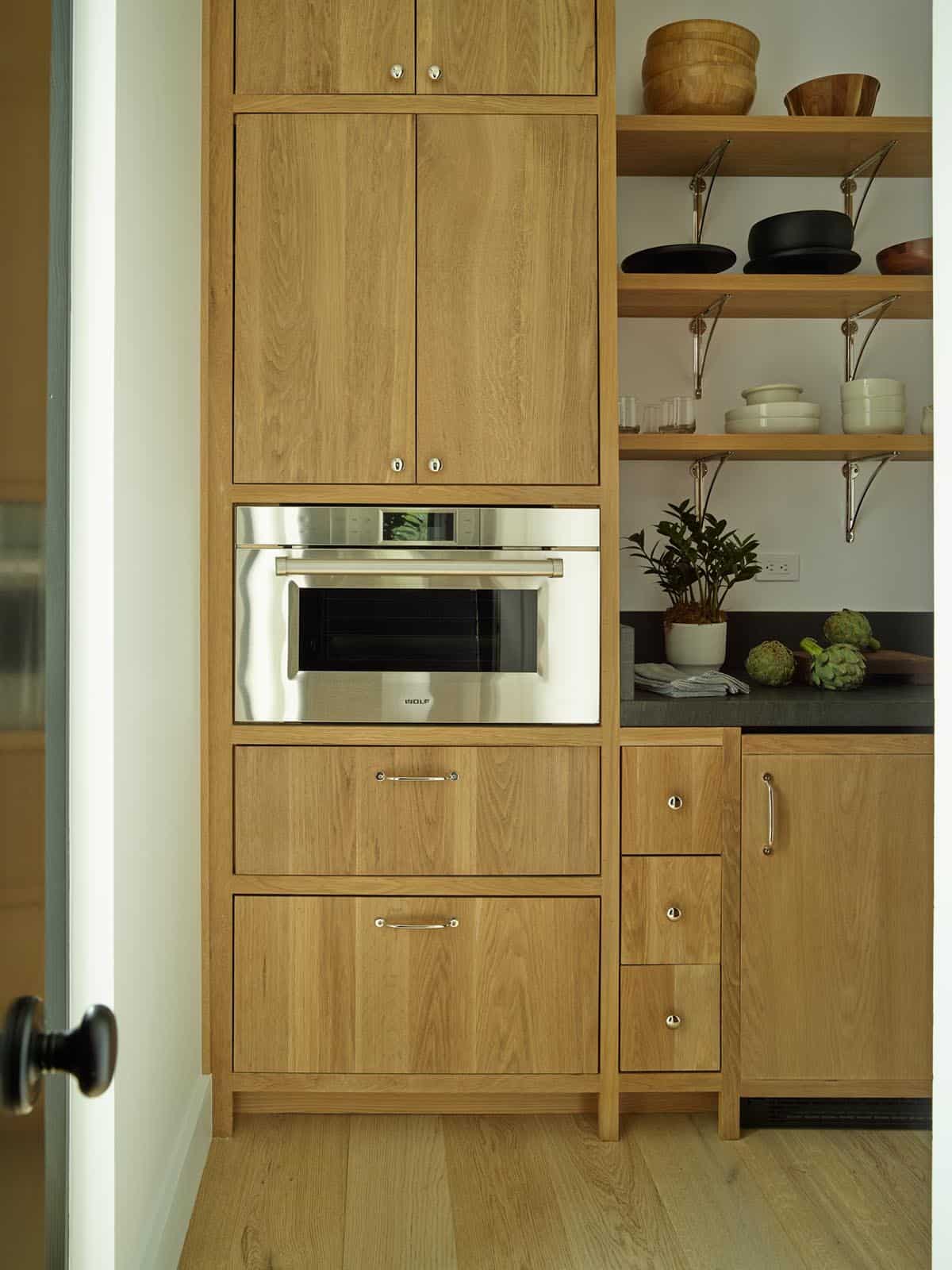 Pantry with built-in oven, wood cabinetry, and open shelving