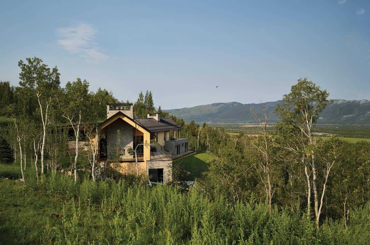 Stone and wood home nestled among aspen trees overlooking valley and mountains