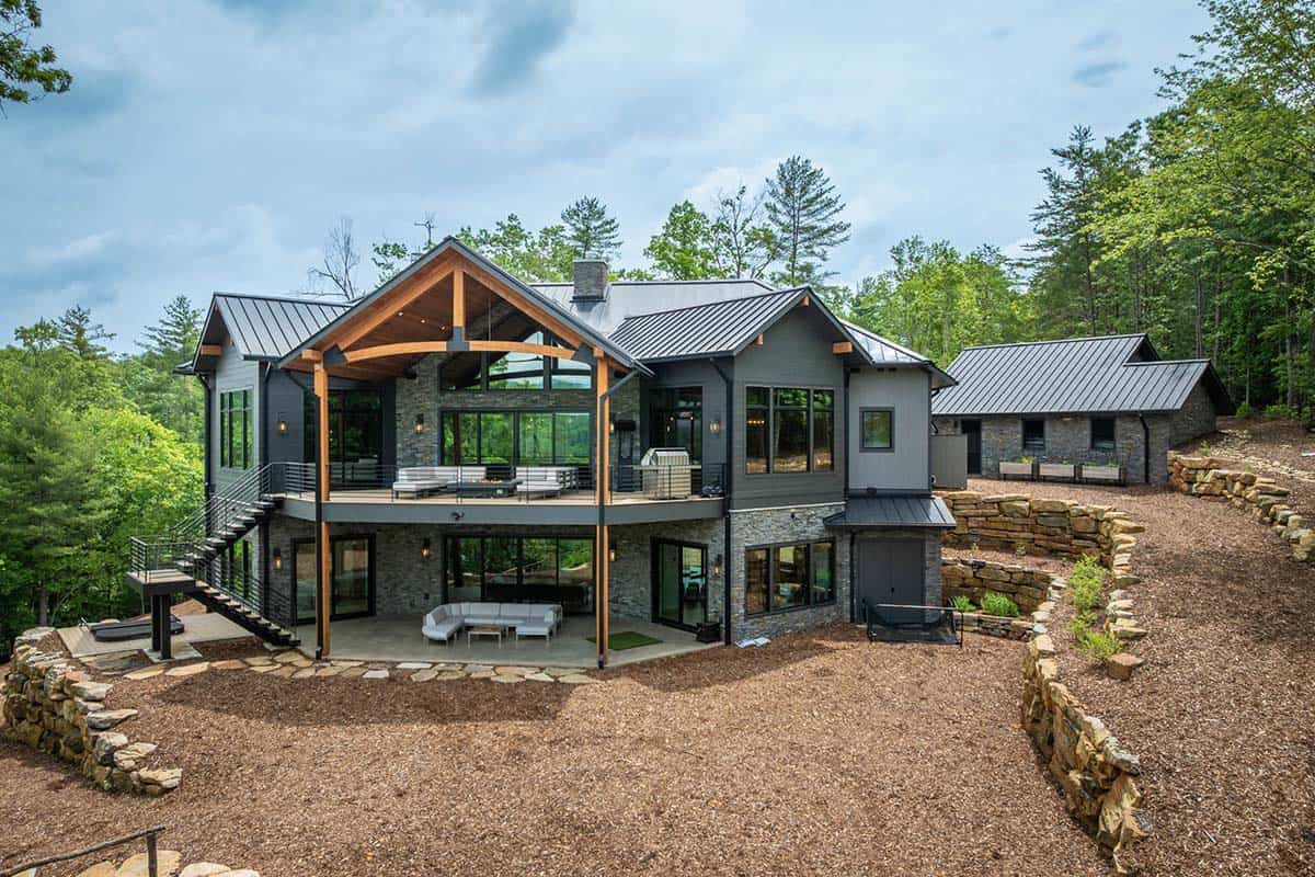 Rear exterior of contemporary home with large glass walls, covered deck, and timber accents