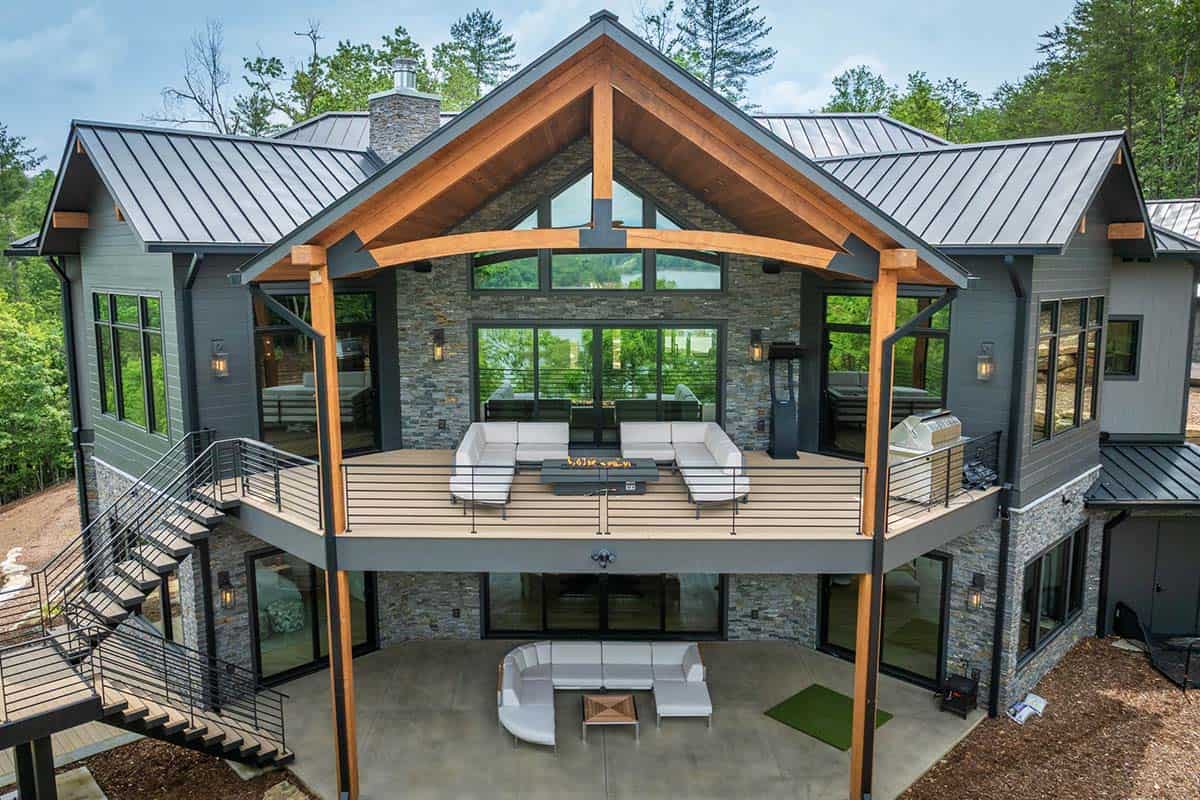 Close-up rear view of deck with timber-frame gable roof, outdoor seating, and lake view through glass