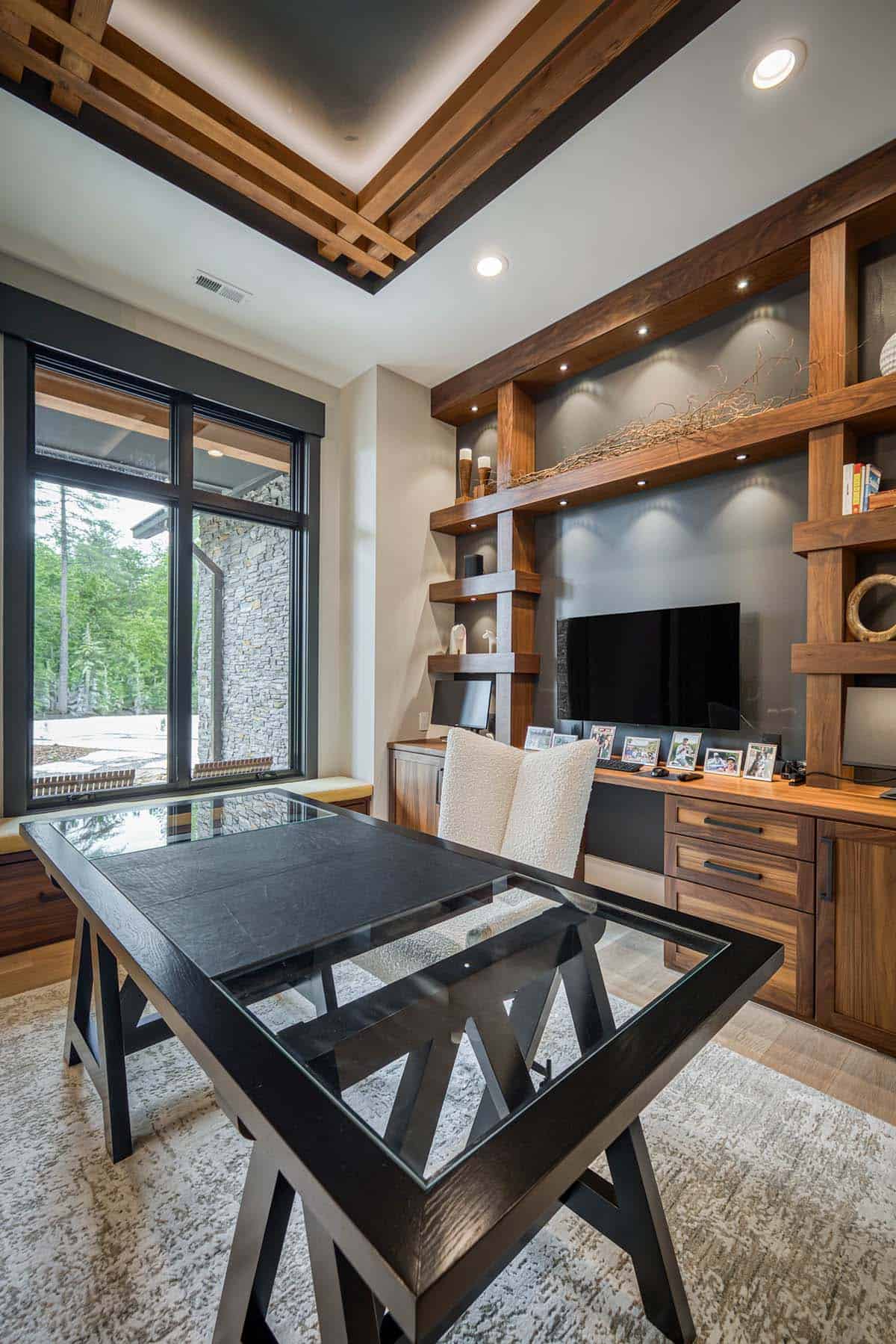 Wide-angle view of home office showing wood ceiling detail, built-in shelves, and glass desk