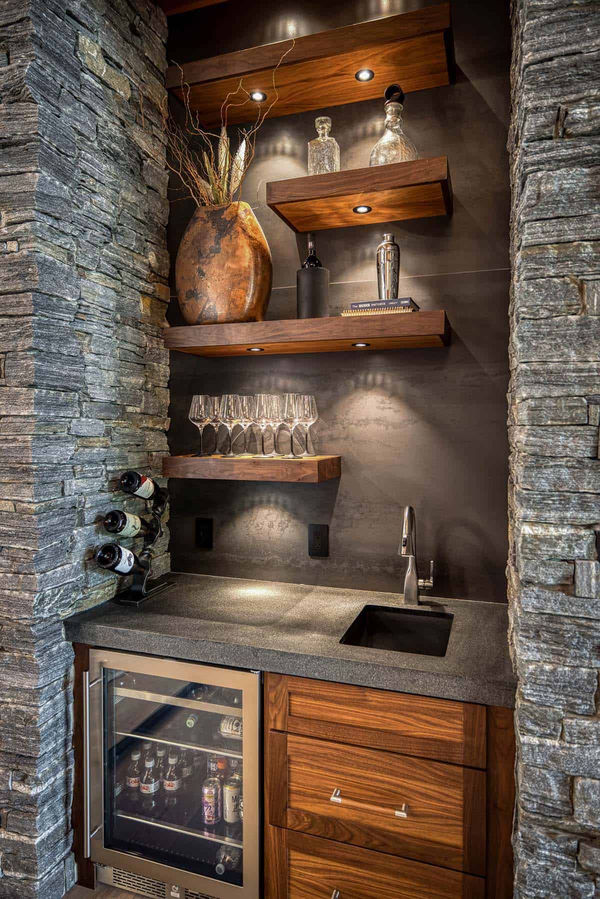 Built-in wet bar niche with floating wood shelves, stone surround, and wine fridge