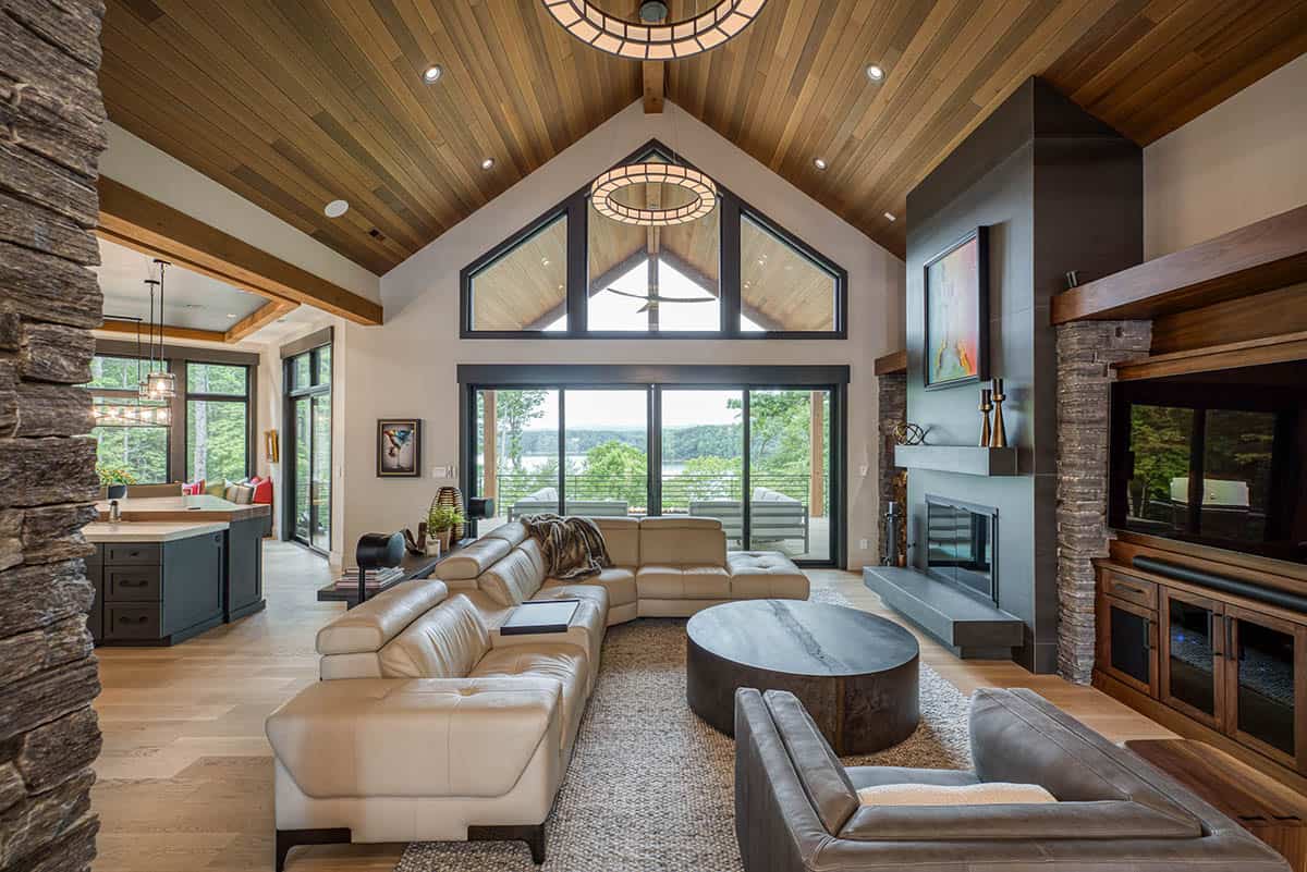 Great room with cathedral wood ceiling, ring pendant lights, stone fireplace, and sectional sofa