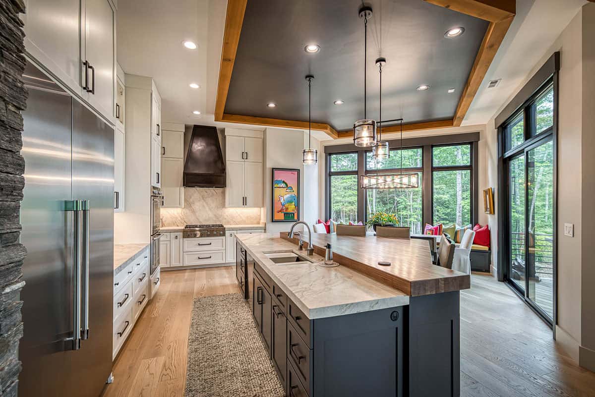 Kitchen with white cabinetry, dark tray ceiling, large island, and stainless refrigerator