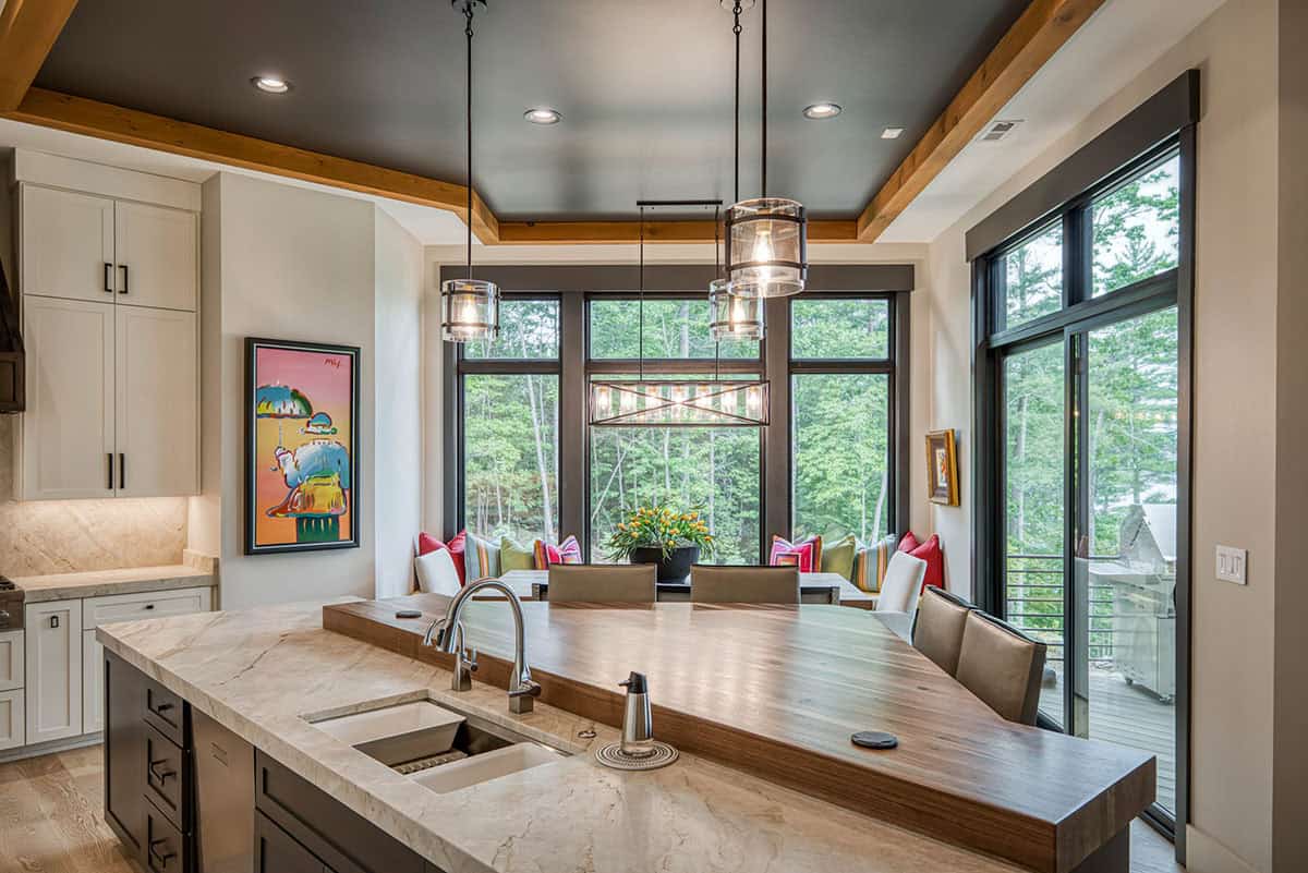 Kitchen island with wood countertop overlooking dining nook with forest views