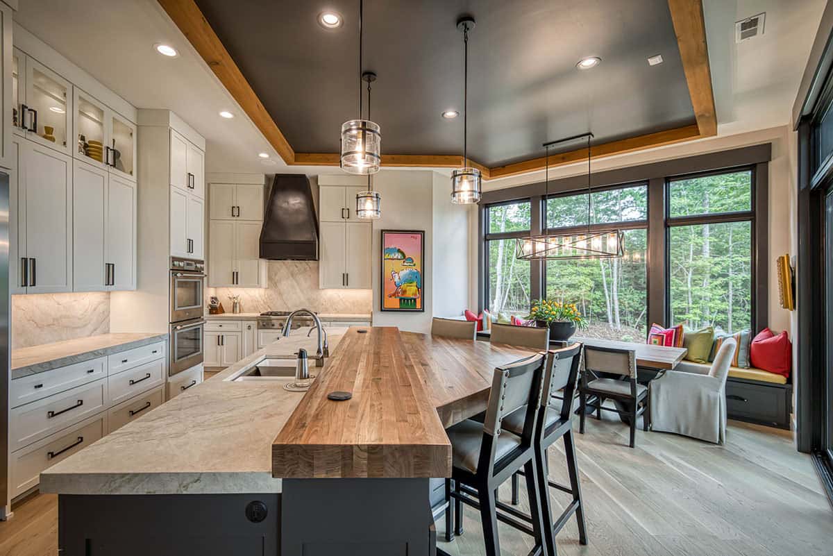 Kitchen with white cabinets, dark ceiling with wood trim, island seating, and dining nook