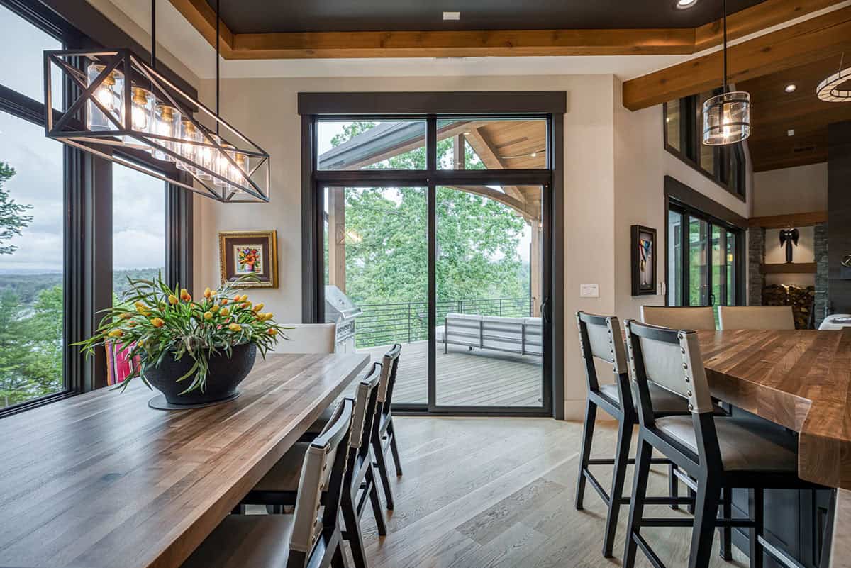 Dining area with wood table, geometric pendant light, and glass door to covered porch