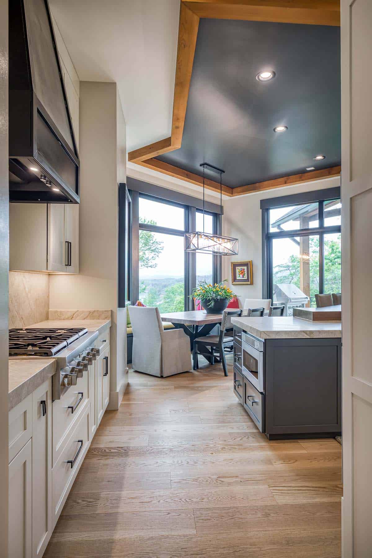 Kitchen view into dining nook with tray ceiling, pendant light, and window seating
