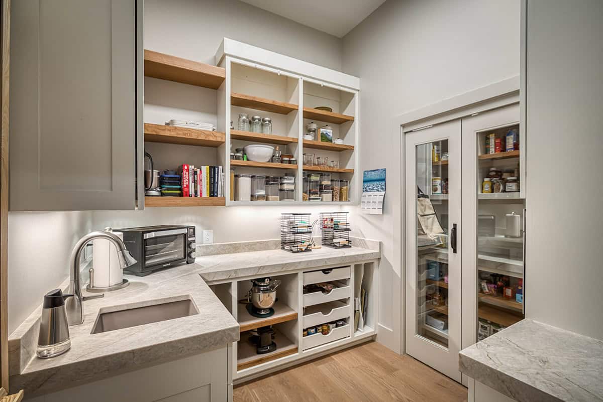 Butler's pantry with open wood shelving, glass-front cabinet, and marble countertop