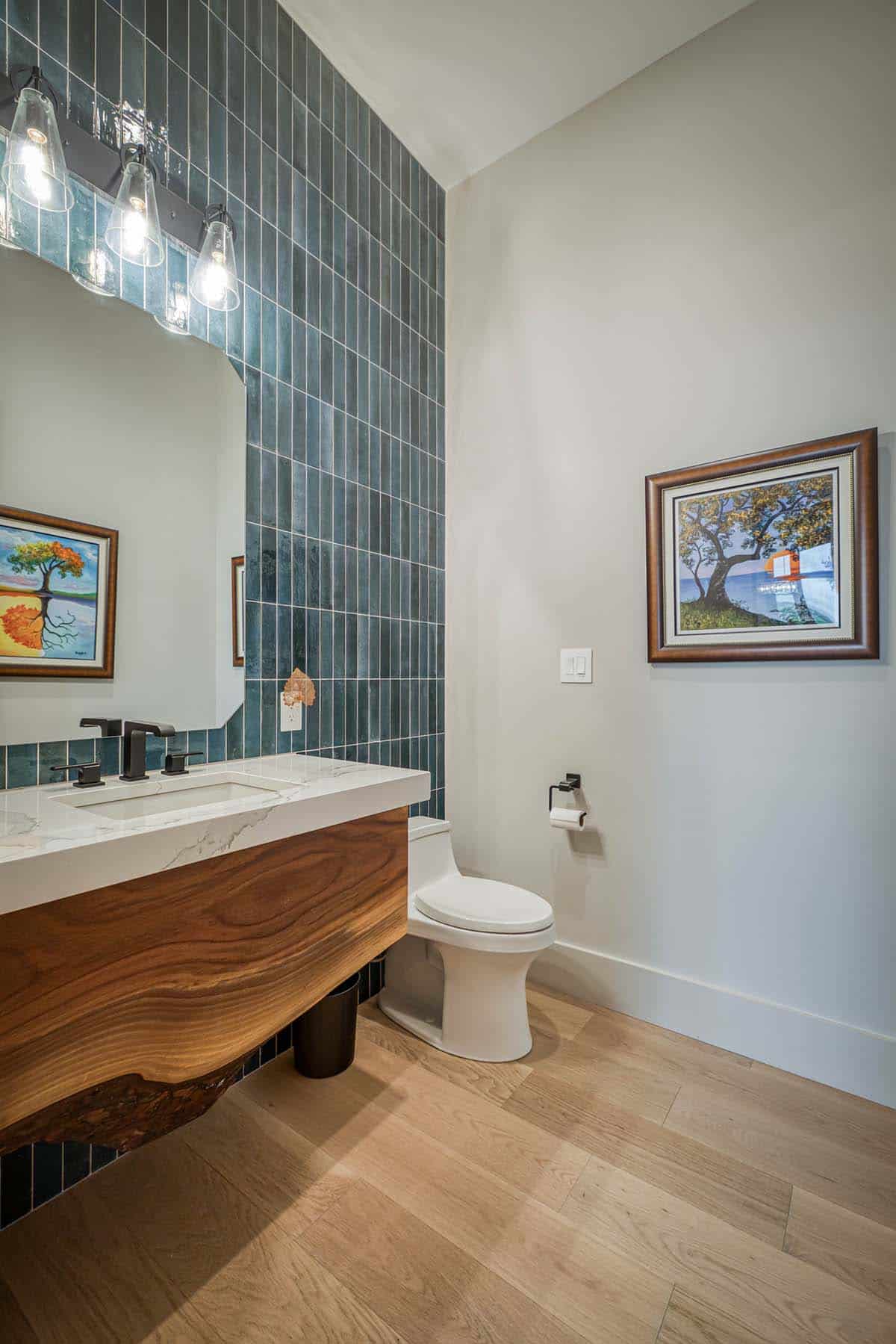 Powder room with dark blue tile accent wall, live-edge wood vanity, and framed art
