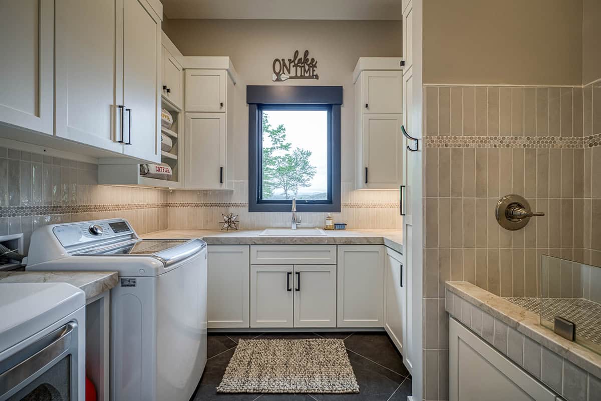 Laundry room with white cabinetry, top-load washer, tile backsplash, and dog wash station